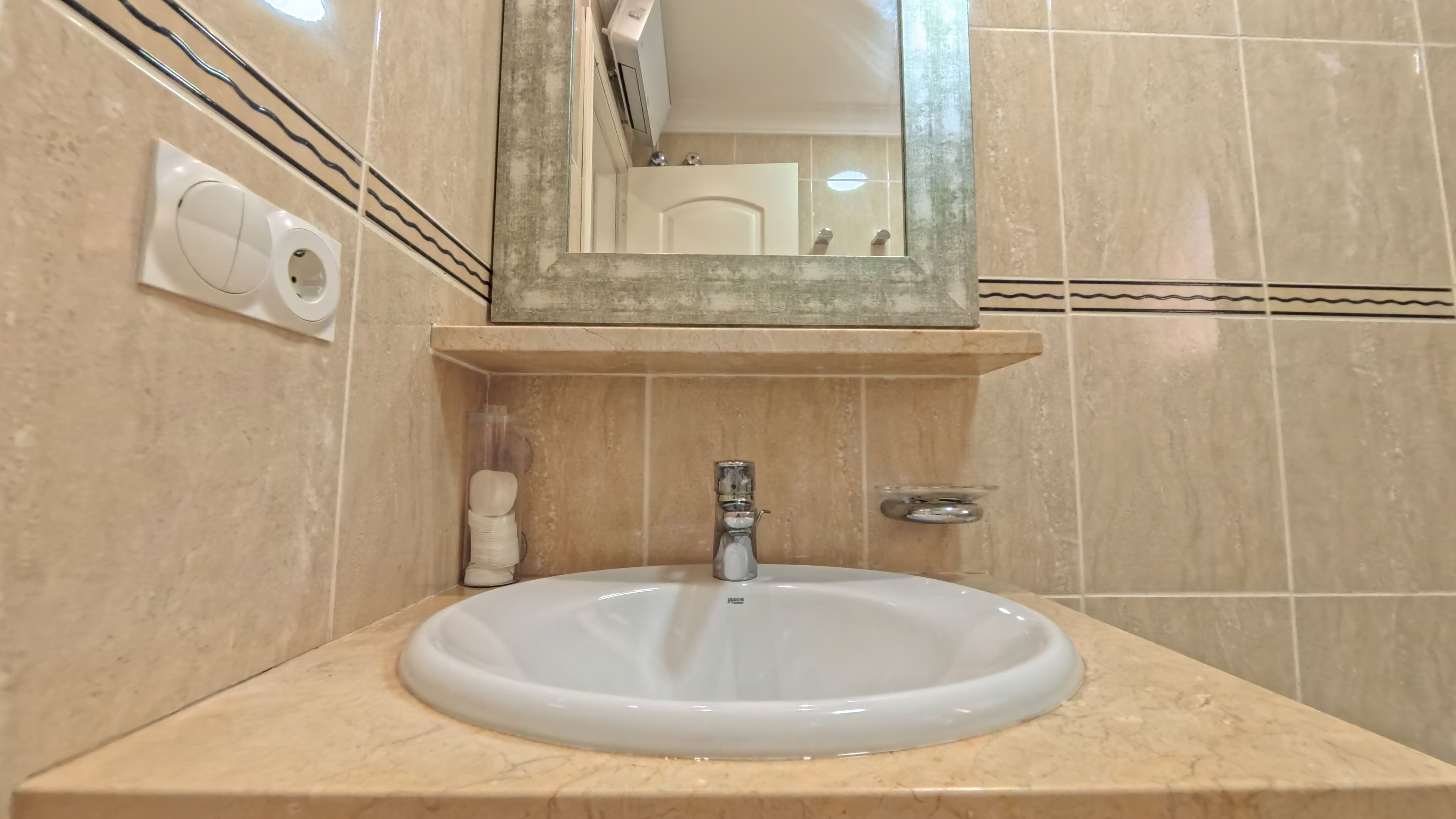 Un baño con un lavamanos blanco, un espejo y un dispensador de toallas.