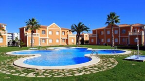 A swimming pool with a circular design, surrounded by a well-maintained lawn and palm trees.