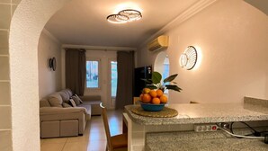 A kitchen with a granite countertop, a bowl of fruit, and a chair. - Solea Mare by Midelisa (oliva nova golf)