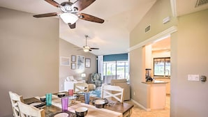 A dining area with a wooden table set for four, a ceiling fan, and a view into the kitchen. - Screened-In Private Pool: Waterfront Home (Cape Coral)