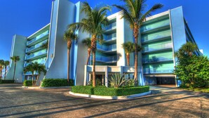 A modern hotel with multiple floors, palm trees, and a well-maintained garden. - Large Beach Condo!! Amazing Ocean Views!! Hutchinson Island, Jensen Beach, FL (Jensen Beach)