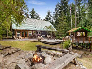 A lodge with a metal roof, wooden deck, and a fire pit.