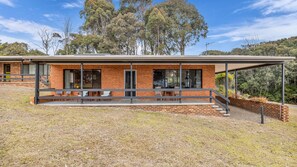 Une maison moderne à deux étages, dotée d’un patio couvert et d’une façade en briques.