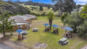 A campground with multiple cabins, picnic tables, and a central gathering area. - Cuttagee Beach Cottage 6 - Tathra Bermagui Rd 3521 (Barragga Bay)