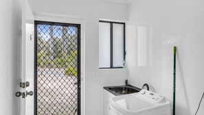 Une salle de bain avec un lavabo blanc, un miroir et une fenêtre.