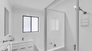 A modern bathroom with a glass shower enclosure, a vanity with a mirror, and a window. - Cuttagee Beach Cottage 6 - Tathra Bermagui Rd 3521 (Barragga Bay)