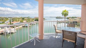 A balcony with a glass table and chairs, overlooking a marina with boats and a cityscape. - Luxury Beach Escape | Steps to Sand (St. Pete Beach)