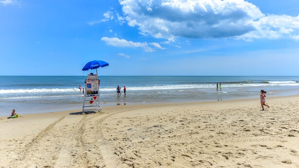 A beach with a lifeguard tower, clear skies, and ocean waves. - 3 Br with pool midtown steps to beach, restaurants and amusements (Ocean City)