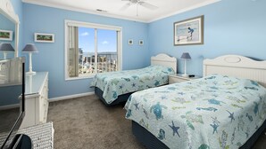 A bedroom with two beds, a ceiling fan, a window with a city view, and a dresser. - 3 Br with pool midtown steps to beach, restaurants and amusements (Ocean City)