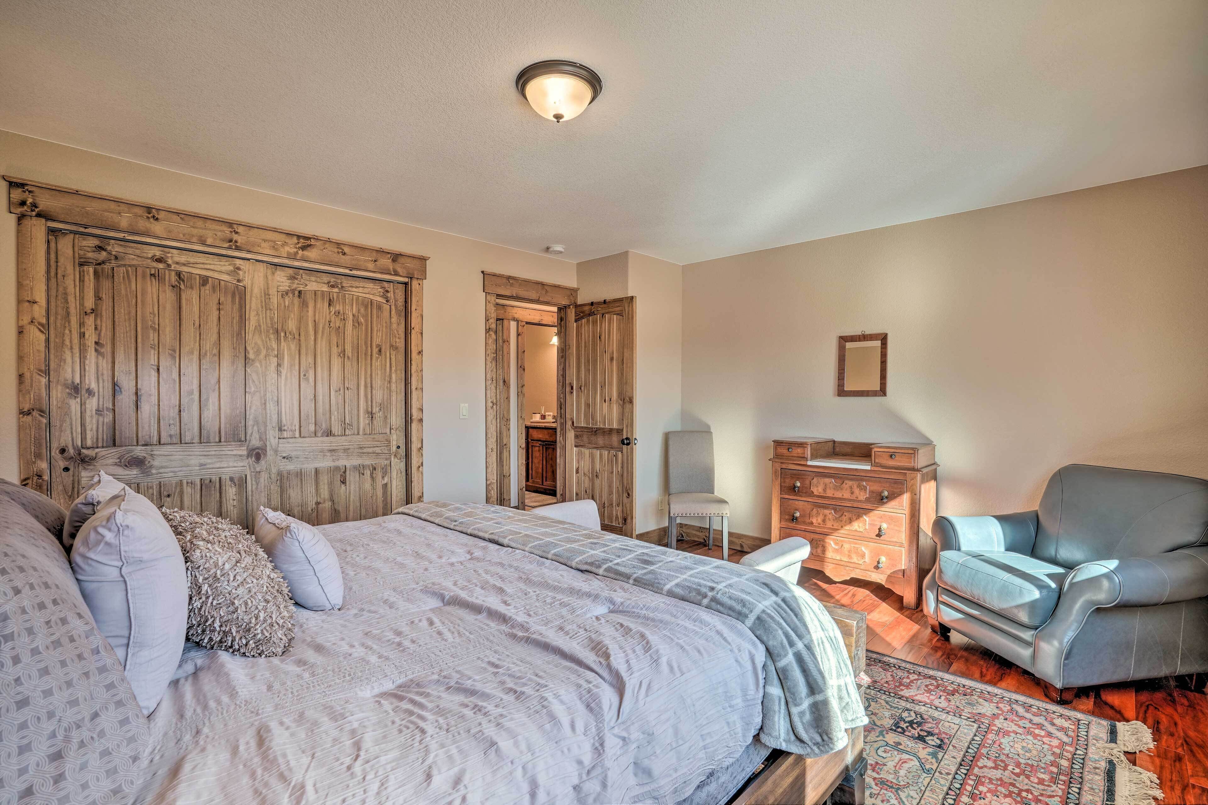 A bedroom with a large bed, a chair, a dresser, and wooden doors.