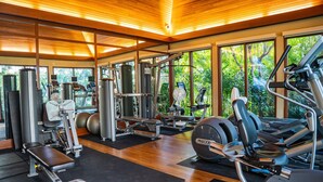 A gym with various exercise equipment, large windows, and a wooden ceiling. - The Watermark (WM1102) Luxury 11th-floor 2 BDR, balcony, AC, remote work (Honolulu)