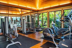 A gym with various exercise equipment, large windows, and a wooden ceiling. - The Watermark (WM1102) Luxury 11th-floor 2 BDR, balcony, AC, remote work (Honolulu)