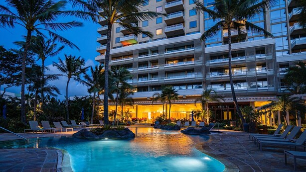 A hotel with a swimming pool surrounded by lounge chairs and palm trees. - The Watermark (WM1102) Luxury 11th-floor 2 BDR, balcony, AC, remote work (Honolulu)