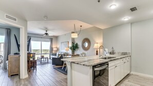 A modern kitchen with a central island, white cabinetry, and a view to the outside. - Balcony & Views! 'Beach Bliss' in Sandestin Resort (Destin)
