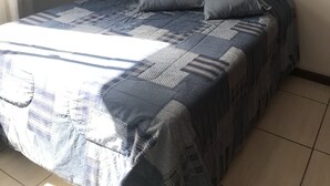 A bedroom with a bed, pillows, a wall-mounted air conditioner, and two feather art pieces. - Near Praia do Forte - second block (Cabo Frio)