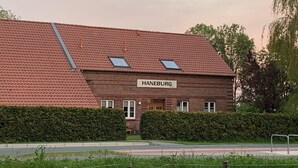 A building with a red-tiled roof, a sign reading "HANEBURG," and a small window on the upper floor.
