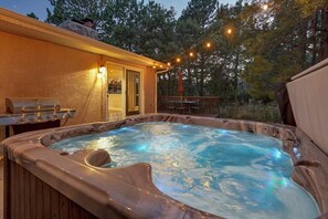 Ein Whirlpool mit Holzterrasse, Grill und Lichterkette.