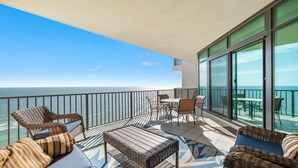 A balcony with wicker furniture, a table, and chairs, overlooking the ocean. - New to the Rental Market!  Lazy River and Water Slide! (Orange Beach)