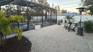 Un espacio al aire libre techado con piscina, sillas de descanso y una pérgola.