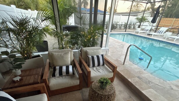 An indoor pool area with lounge chairs and a small table. - Newly remodeled close to downtown and beaches 3/2 heated pool and screened lanai (Sarasota)