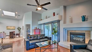 A spacious living room with a fireplace, leather sofas, a coffee table, and a ceiling fan. - Private Patio + Pool Access: Quiet Condo in Tempe (Tempe)