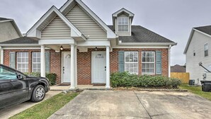 A two-story house with a front porch, brick facade, and a car parked in the driveway. - Tidy Tallahassee Townhome ~ 7 Mi to Downtown! (Tallahassee)