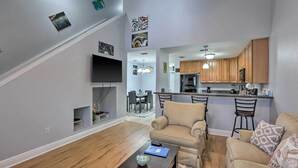 A modern living room with a sofa, coffee table, and a staircase leading to a dining area. - Tidy Tallahassee Townhome ~ 7 Mi to Downtown! (Tallahassee)