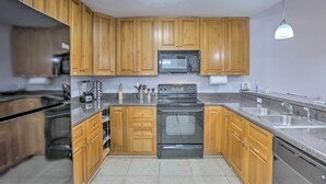 A kitchen with wooden cabinets, a stainless steel refrigerator, a microwave, an oven, and a sink. - Tidy Tallahassee Townhome ~ 7 Mi to Downtown! (Tallahassee)
