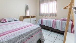 A bedroom with two beds, a wooden wardrobe, a mirror, and a window with curtains. - Apê no melhor de LagoaNova Por Carpediem (Natal)