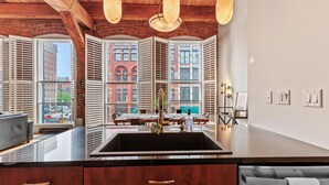 A kitchen with a large window, a sink, and wooden cabinets. - Luxe Loft Downtown (Indianapolis)