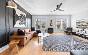 A modern living room with a leather sofa, a round coffee table, and a patterned rug. - Downtown Lake Geneva Rooftop on Main | Parking | Rooftop Deck (Lake Geneva)