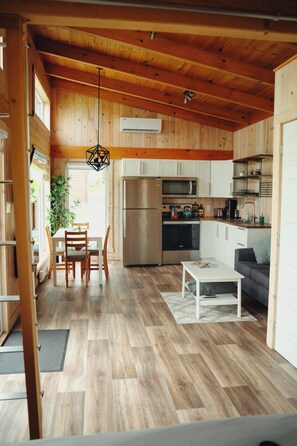 A modern kitchen with wooden cabinets, a stainless steel refrigerator, and a microwave. - Chalets Nautika (Gaspé)