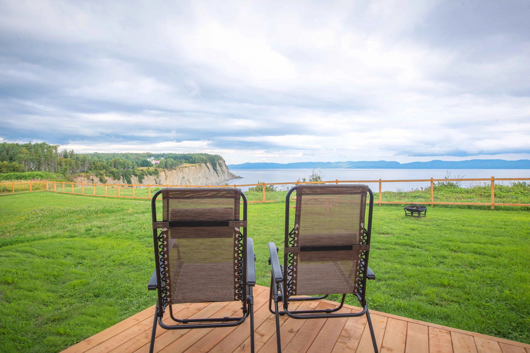 Two chairs facing a scenic view of a cliff and water.