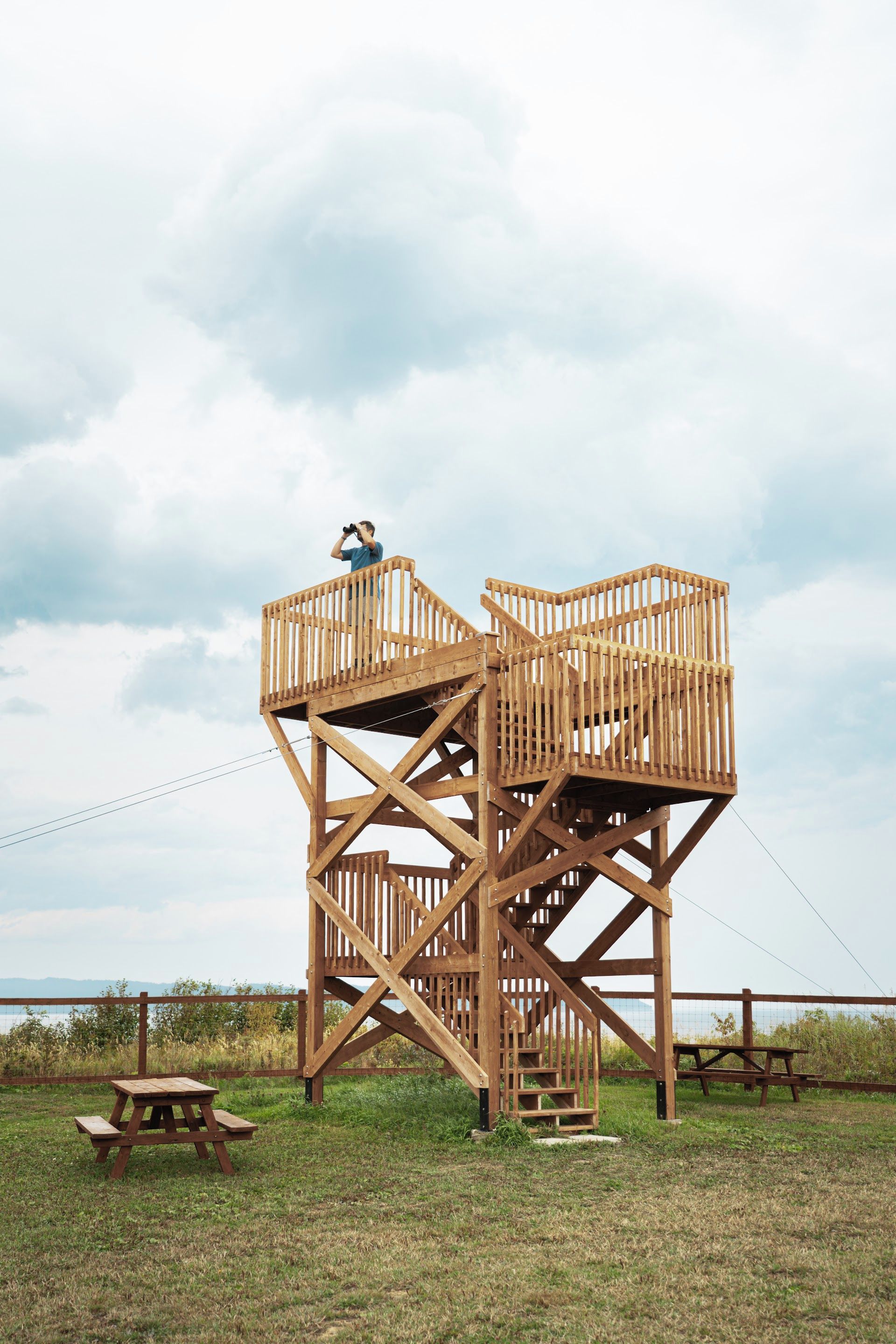 Una torre de madera con escalera y una mesa de picnic en un área con césped.