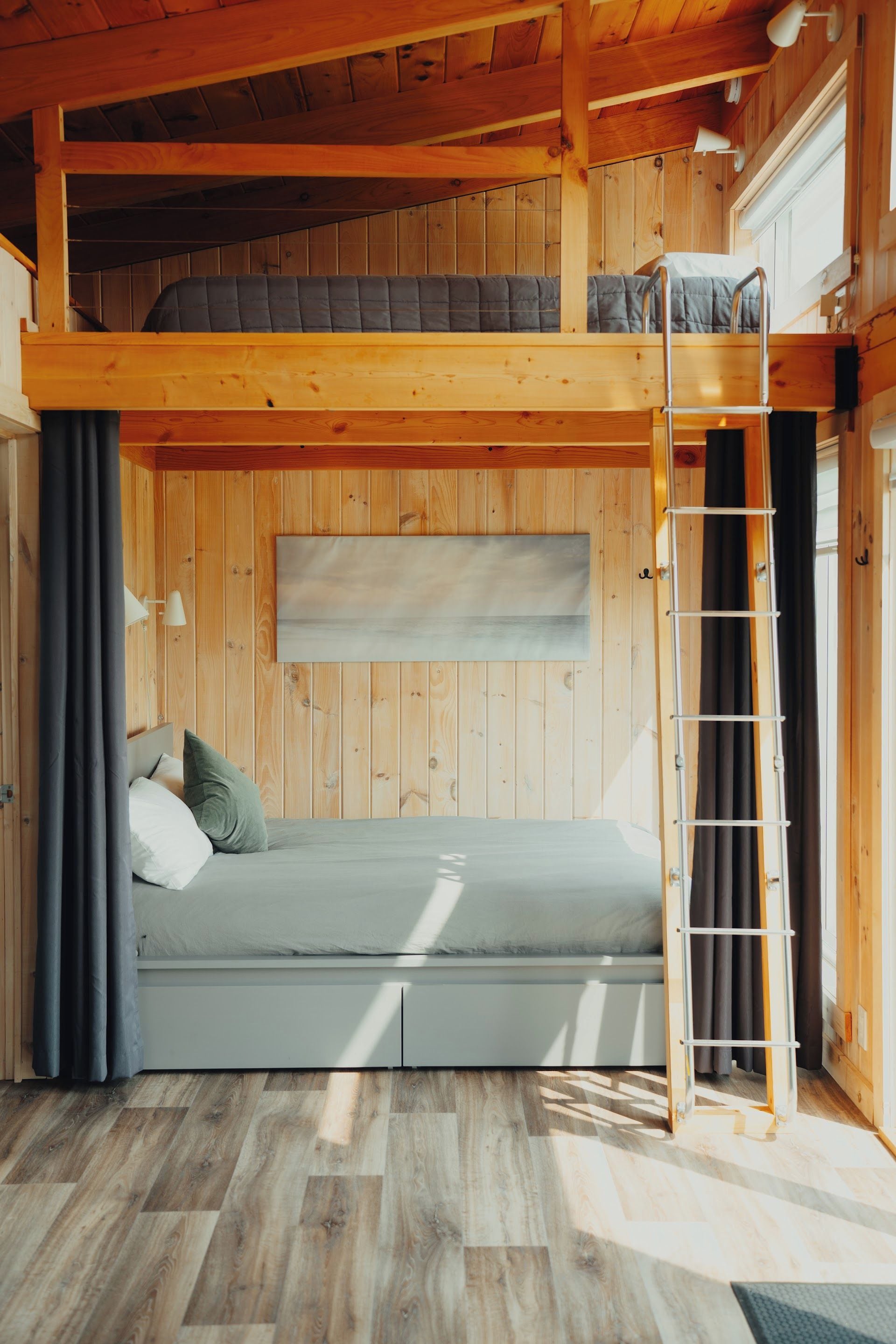 Habitación con literas, un sofá cama y una ventana con cortinas.