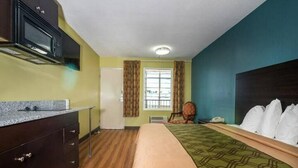 A hotel room with a bed, a desk, a microwave, and a window with curtains. - King Bed Efficiency Non-Smoking at Royal Extended Stay Hotel Selma I-95 (Selma)
