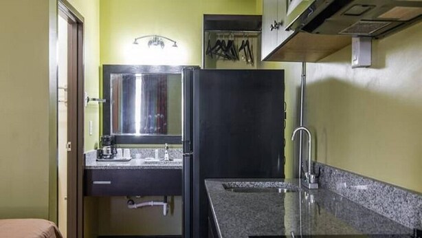 A compact kitchen with a countertop, sink, and a stove. - King Bed Efficiency Non-Smoking at Royal Extended Stay Hotel Selma I-95 (Selma)