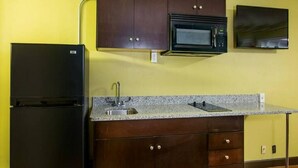A kitchen with dark wooden cabinets, a black refrigerator, a microwave, and a granite countertop. - King Bed Efficiency Non-Smoking at Royal Extended Stay Hotel Selma I-95 (Selma)
