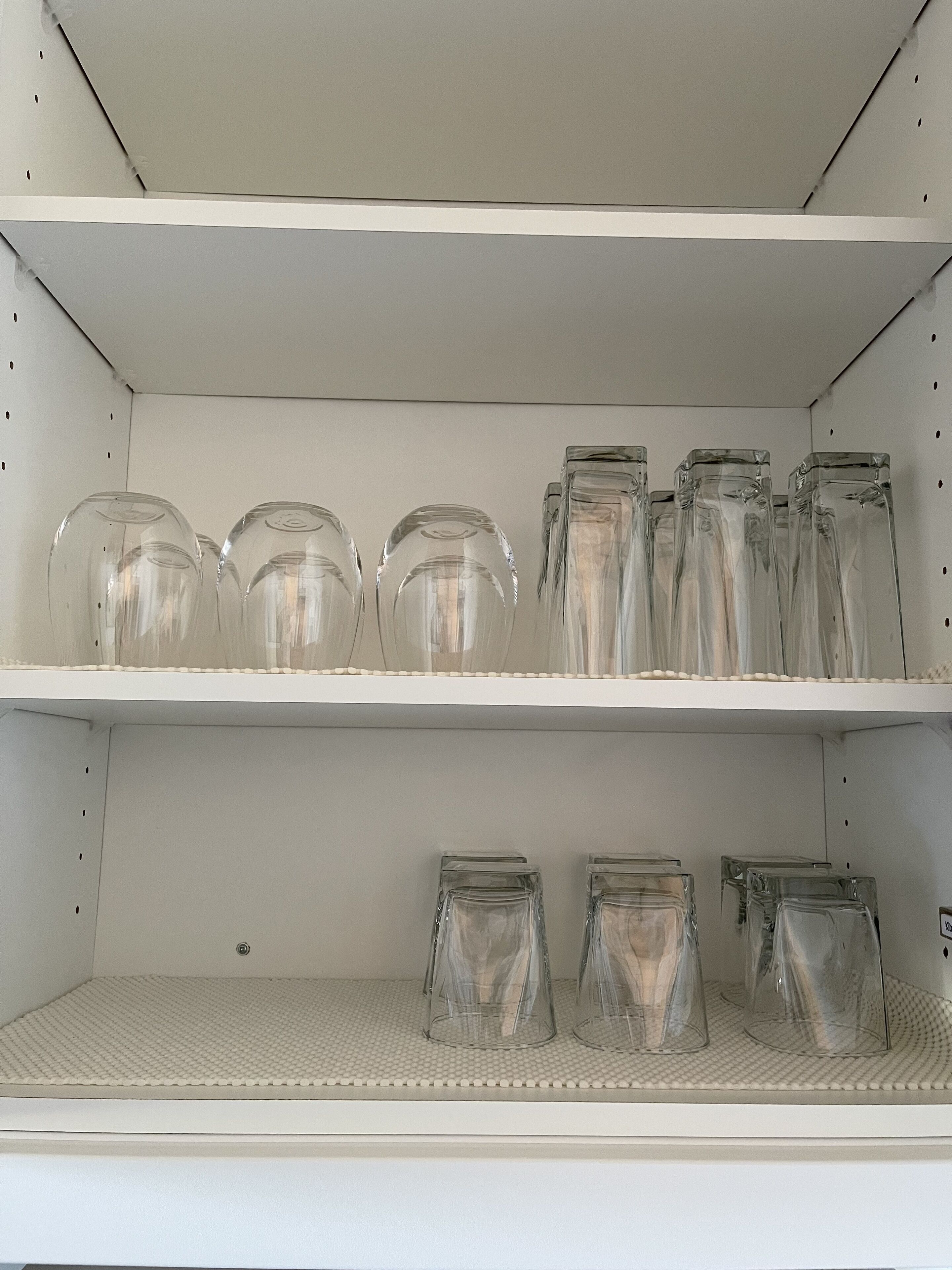 Une étagère blanche sur laquelle sont disposés des bocaux en verre transparent de différentes tailles.