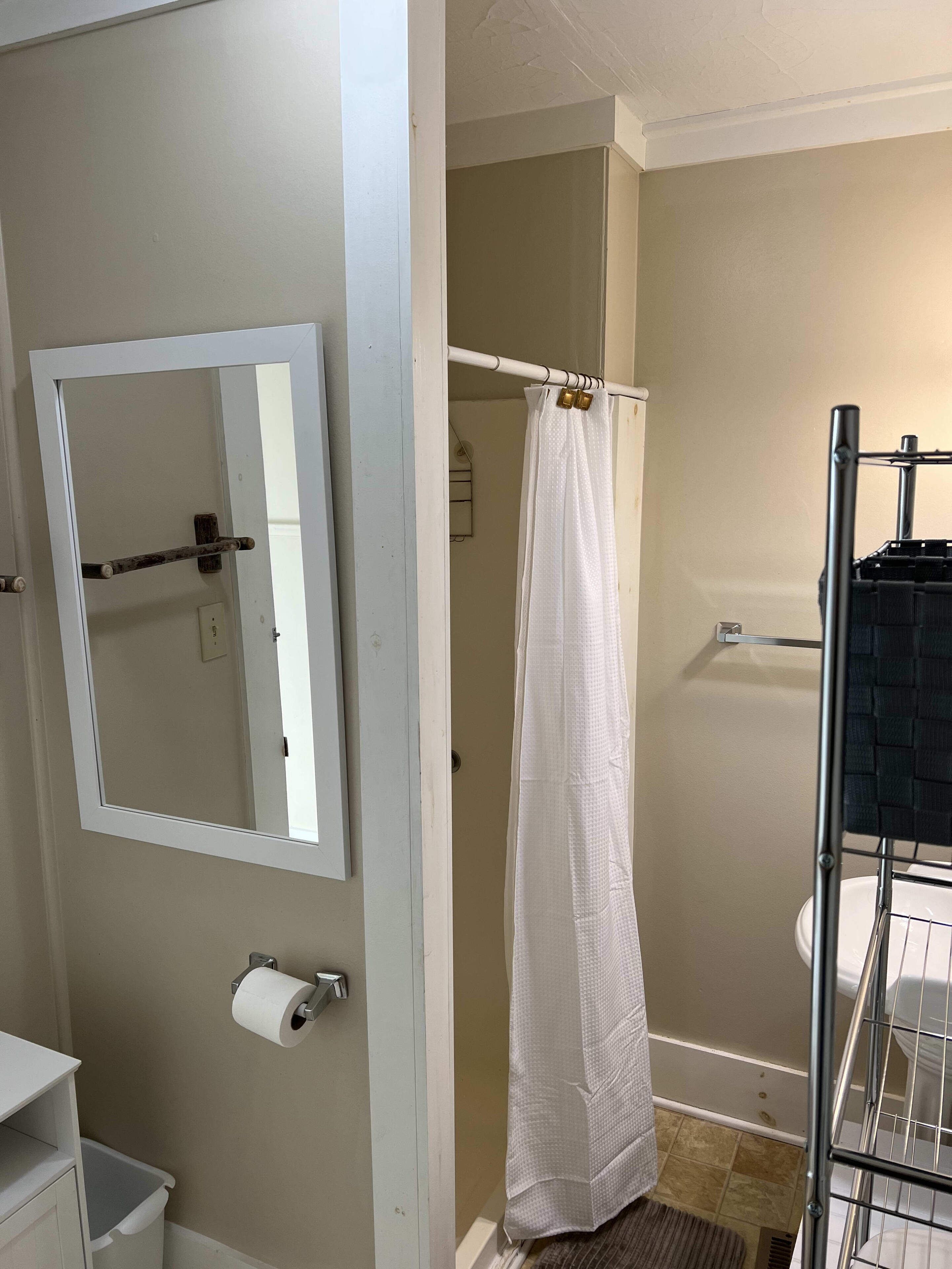 Un baño con inodoro, cortina de ducha, toallero y espejo.