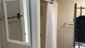 Un baño con inodoro, cortina de ducha, toallero y espejo.