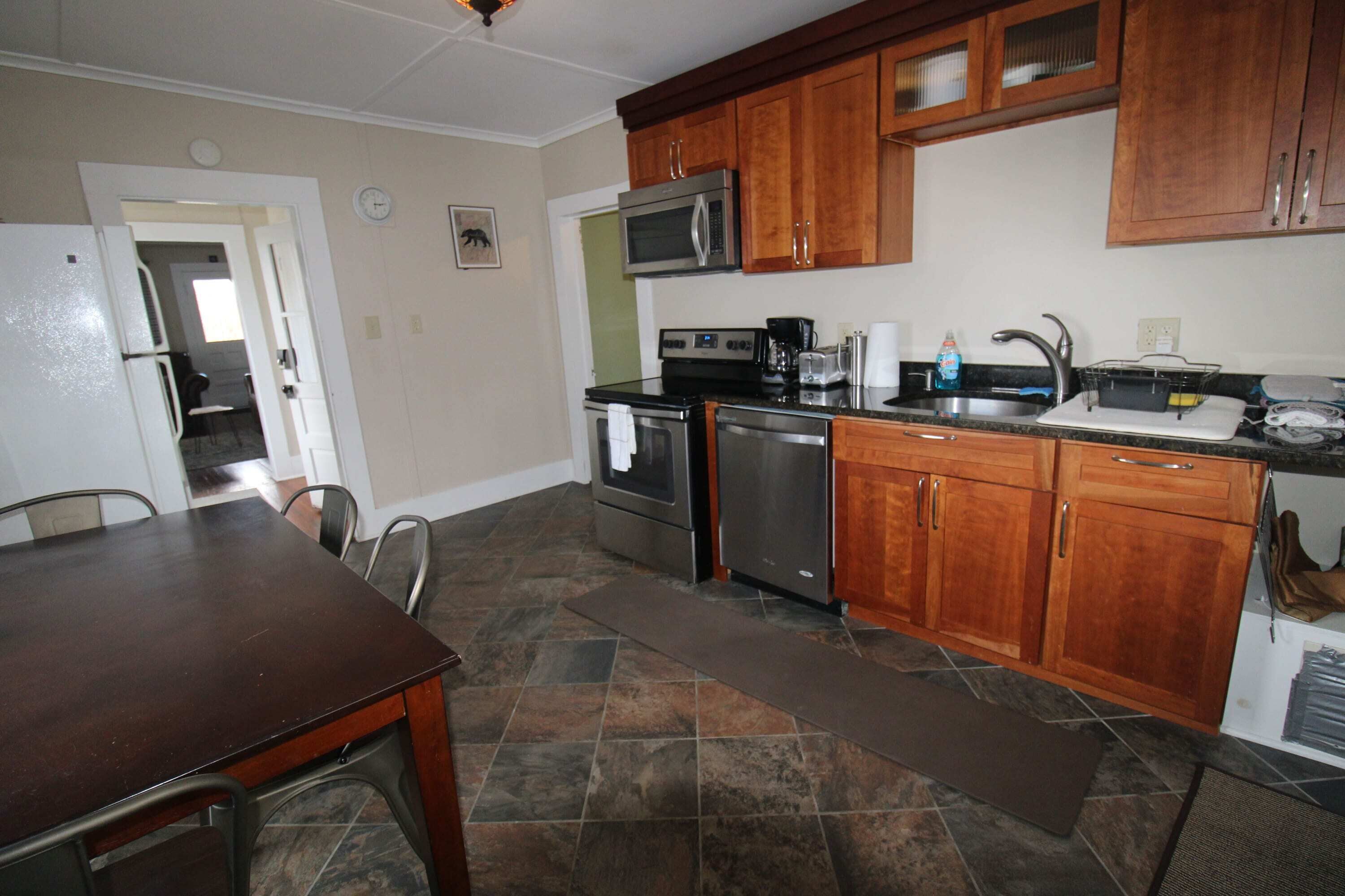 A kitchen with wooden cabinets, a microwave, a stove, and a sink.