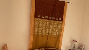 Ein Schlafzimmer mit einem Bett, einem Nachttisch, einer Holzkommode und einem Fenster mit Vorhängen.