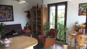 Ein gemütliches Wohnzimmer mit einem Holztisch, einer Couch, einem Sessel und einer Vitrine mit Glastüren.