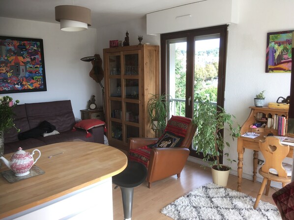 A cozy living room with a wooden coffee table, a sofa, a chair, and a cabinet with glass doors.