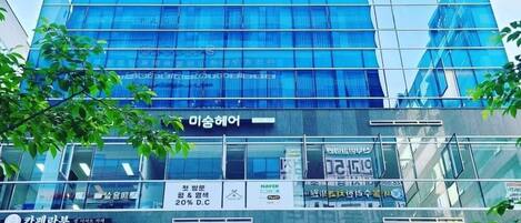 Un moderno edificio de hotel con fachada de vidrio y señalización en coreano.