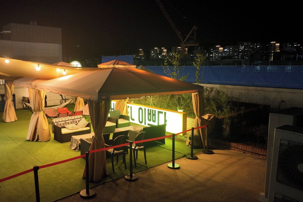 Un espacio para comer al aire libre con una carpa, mesas, sillas y un cartel.