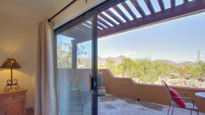 A room with a sliding glass door leading to an outdoor patio with a cactus, a chair, and a table. - 'La Paloma' - Full Circle Ranch Studio w/ Views! (Cave Creek)