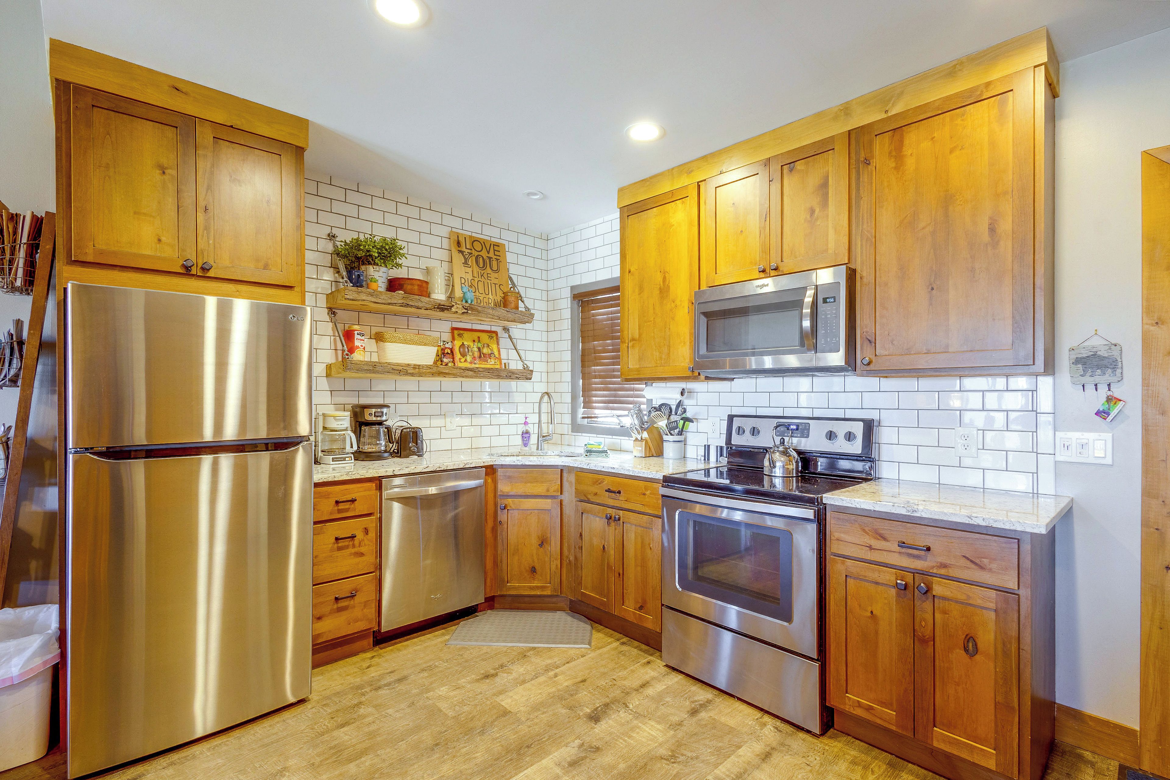 A kitchen with wooden cabinets, stainless steel appliances, and a white tiled backsplash.