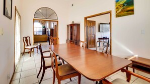 A dining area with a long wooden table and chairs, a chandelier, and a painting on the wall.